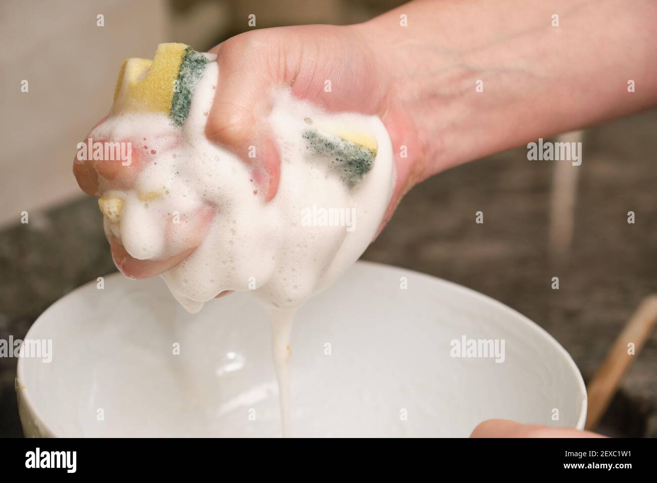 Immagine ritagliata di un uomo che stringe la spugna con schiuma di sapone. Pulizia delle faccende domestiche. Foto Stock