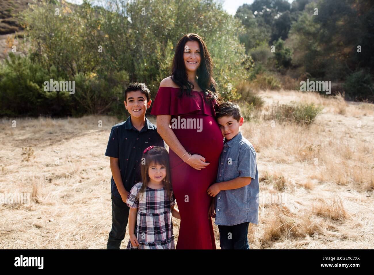 Madre incinta in posa con tre bambini in campo a San Diego Foto Stock