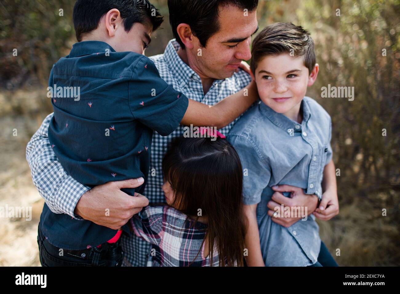 Papà che tiene tre bambini in campo a San Diego Foto Stock