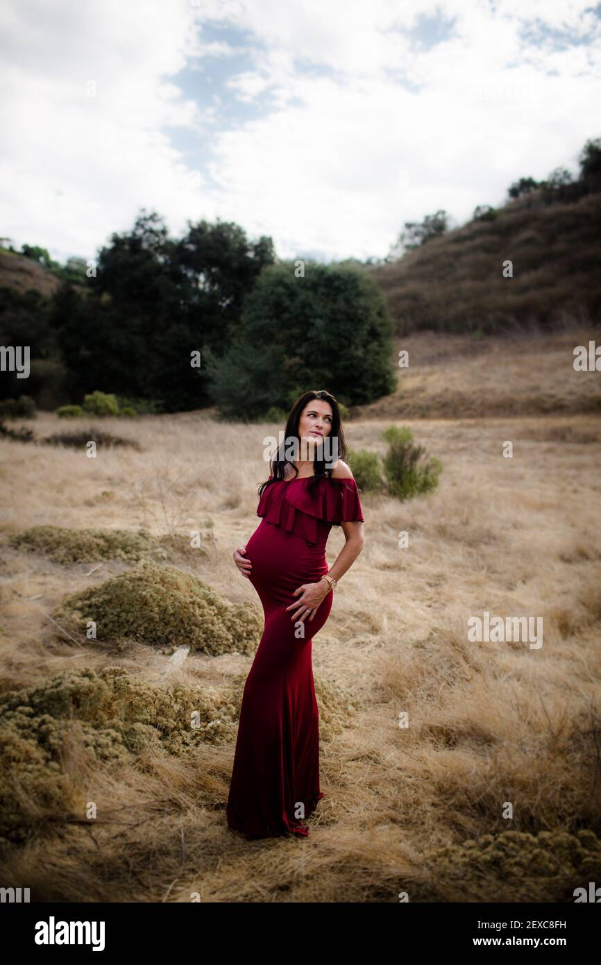 Donna in attesa in posa sul campo in Red Dress a San Diego Foto Stock
