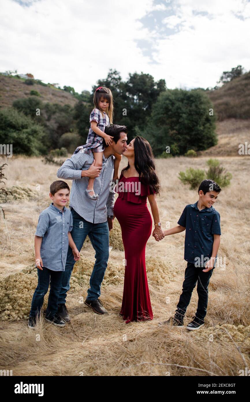 Mamma e papà Kissing con bambini in campo a San Diego Foto Stock