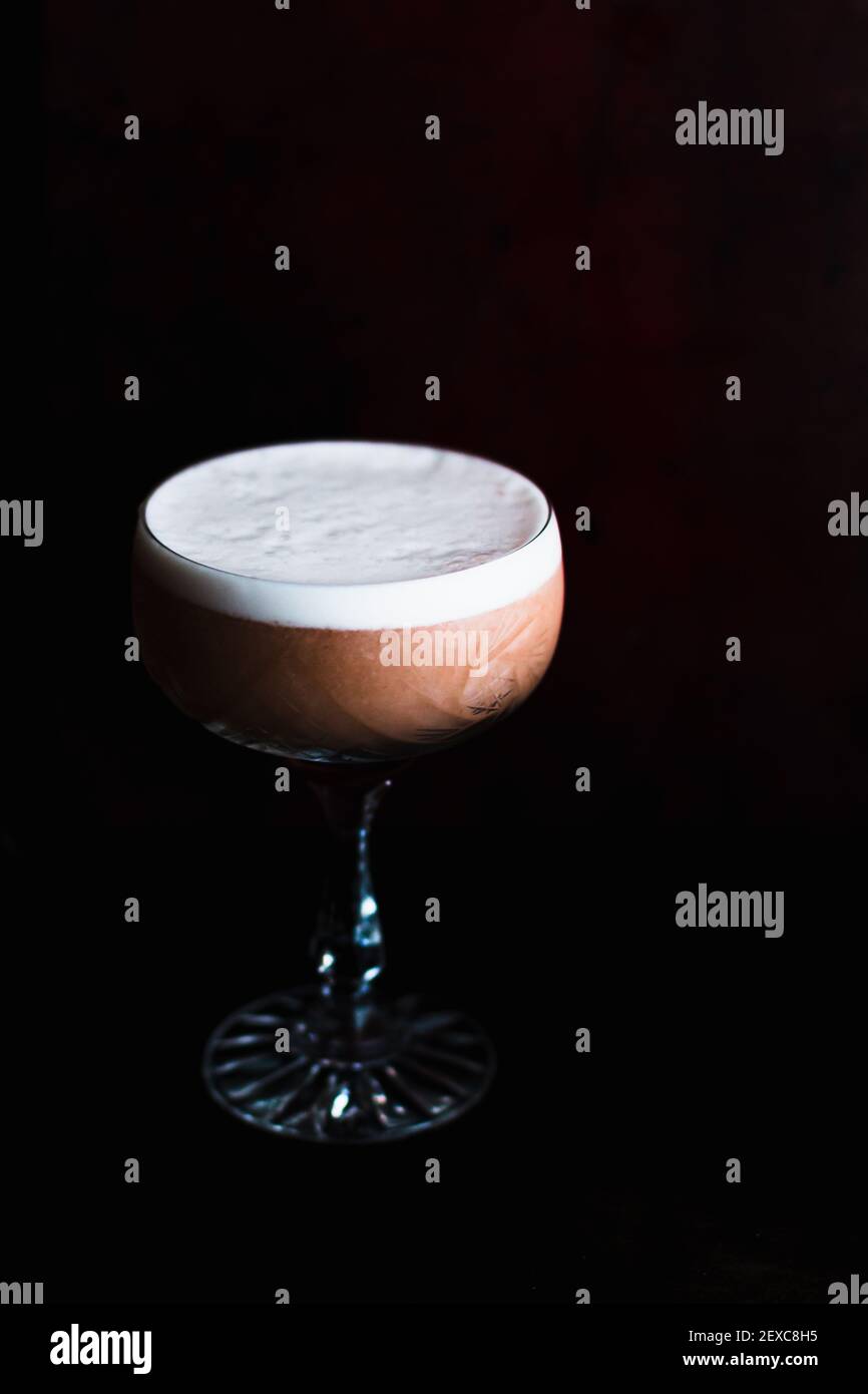 Gin pink sour drink in un bicchiere coupé con schiuma bianca all'uovo Foto Stock