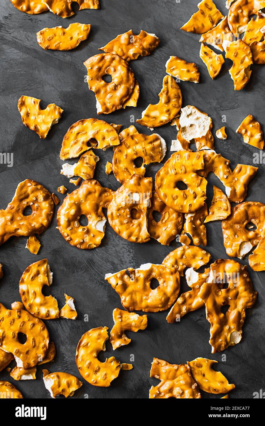 Disposizione flatlay di pretzel snacking sparsi su una superficie di grigio scuro. Foto Stock