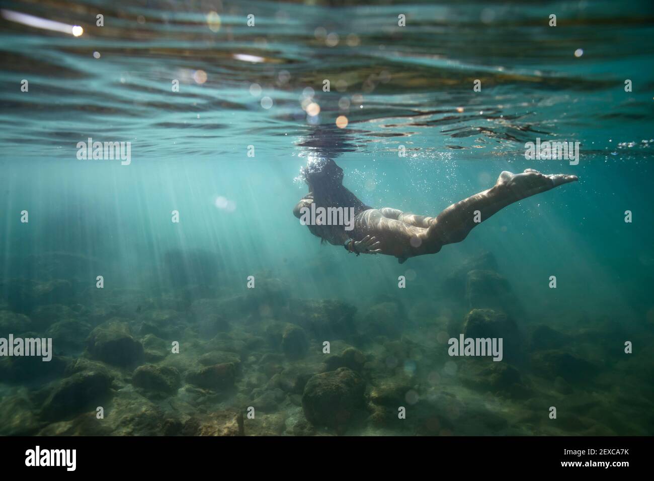 femmina che nuota lontano dalla macchina fotografica e fino alla superficie di oceano poco profondo Foto Stock