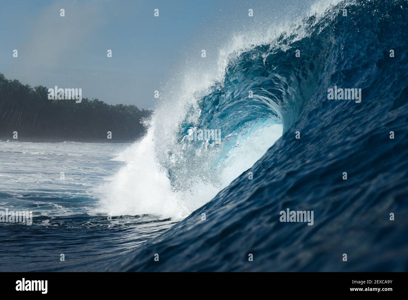 Un'onda blu che si infrange su una spiaggia in mare Foto Stock
