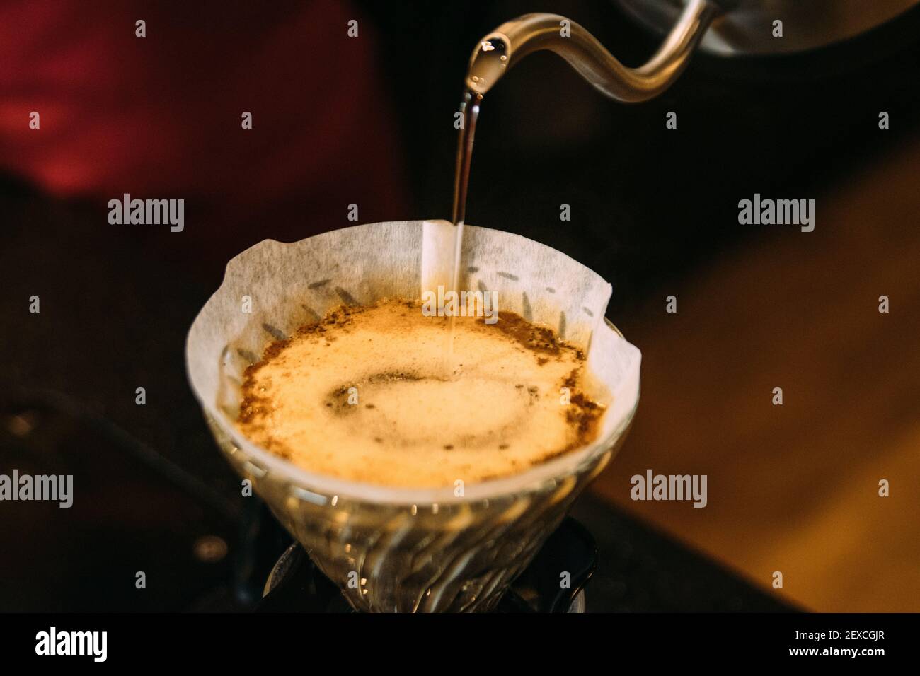 Versare l'acqua nel filtro del caffè al bar Foto Stock