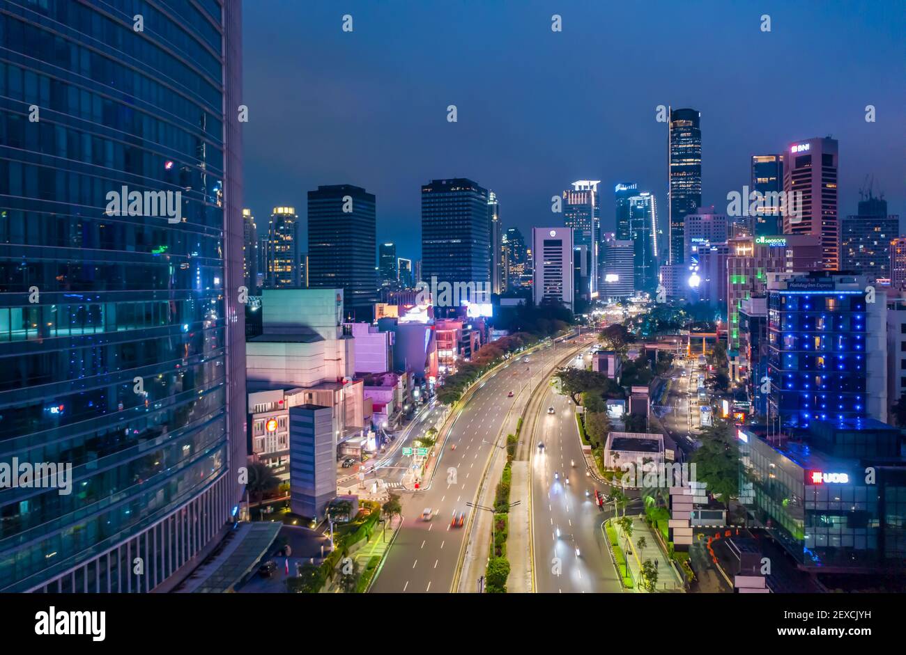 Vista aerea notturna del traffico in rapido movimento sull'autostrada a più corsie attraverso il centro città con grattacieli Highway attraverso il centro di Giacarta, Indonesia Foto Stock