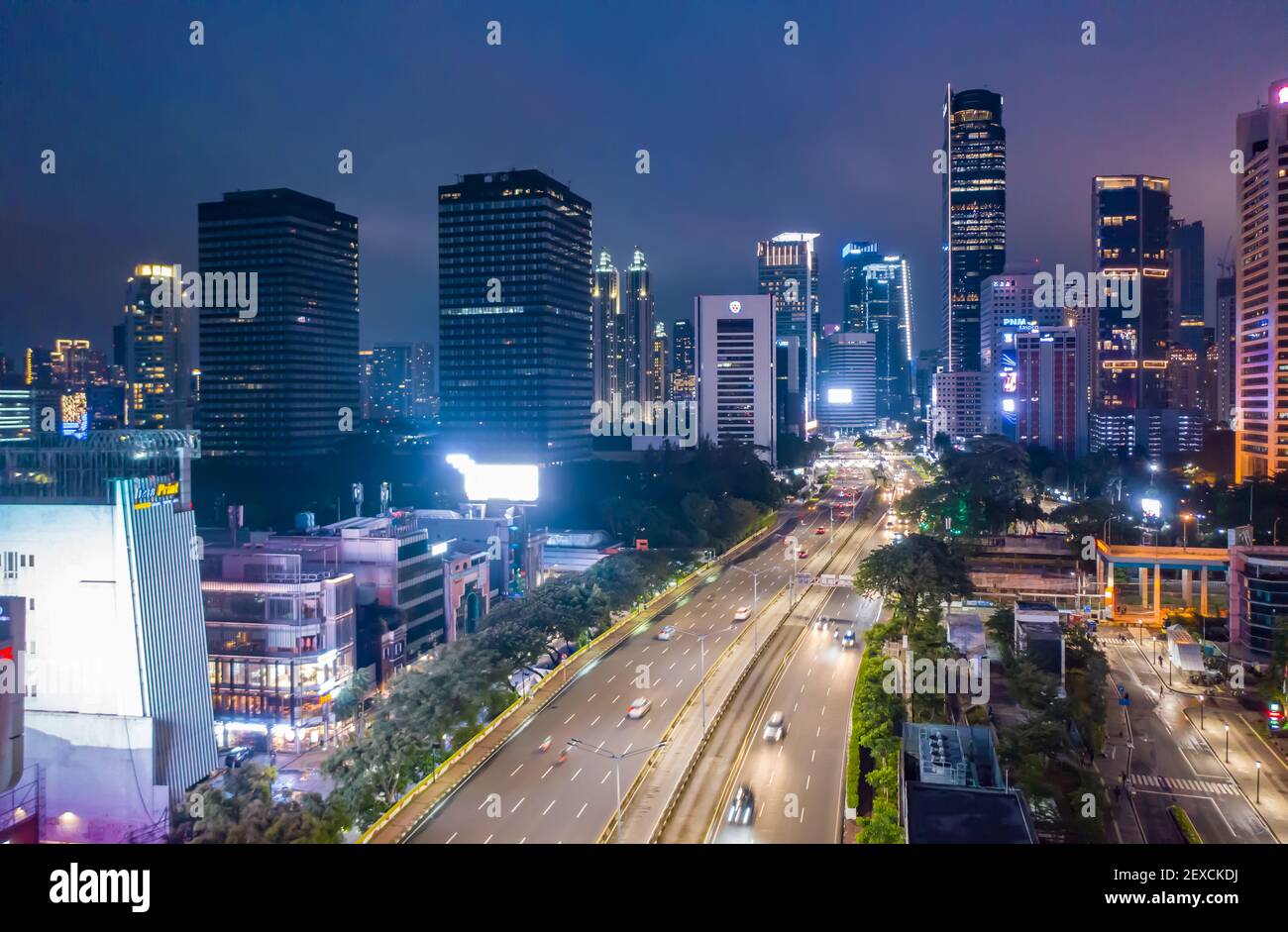Vista del traffico veloce notturno attraverso il moderno centro cittadino urbano con grattacieli a Giacarta, Indonesia Vista aerea dell'autostrada a più corsie attraverso la città Foto Stock