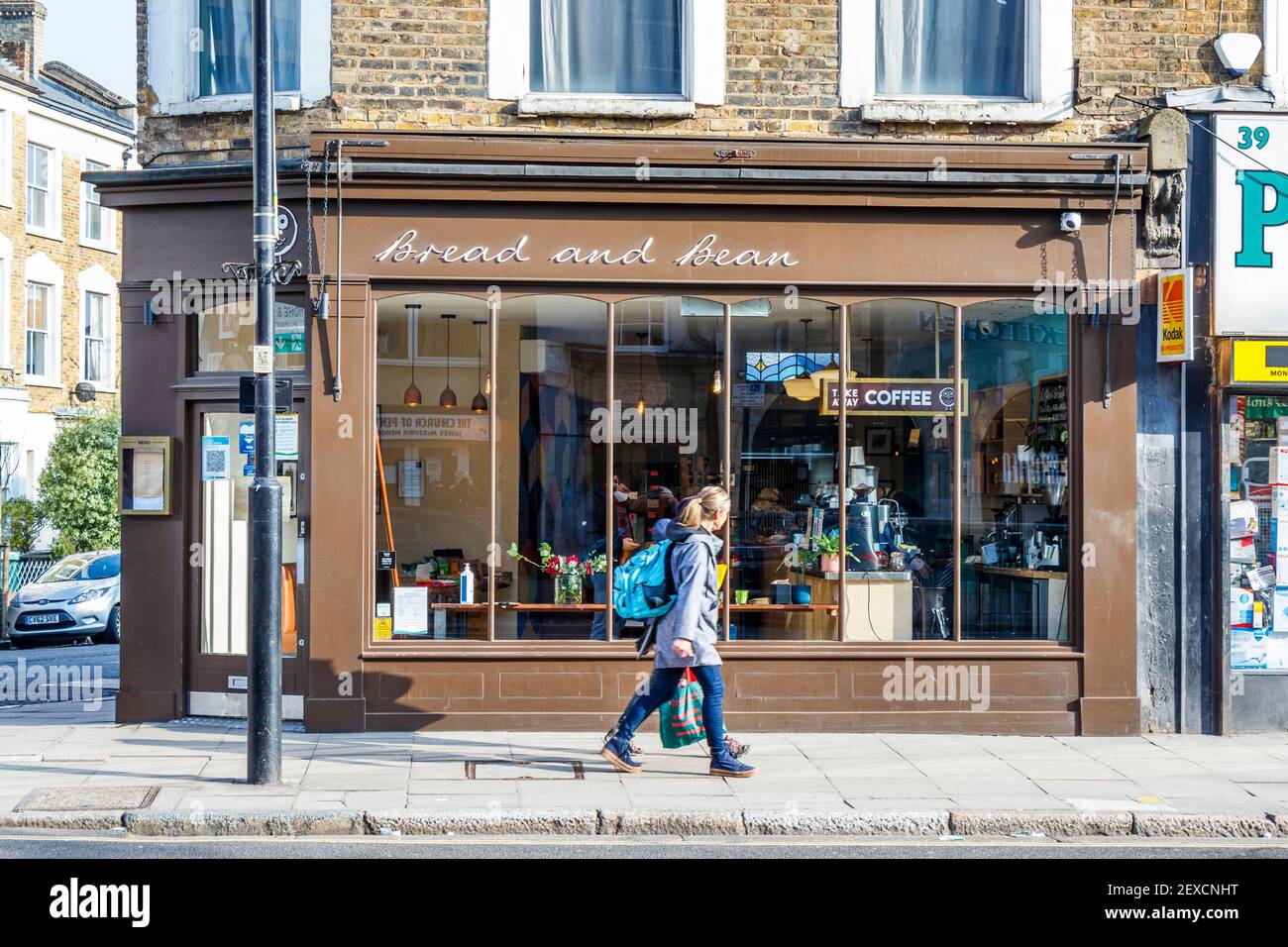 Due donne passano accanto a Bread and Bean, una caffetteria indipendente in Junction Road, Islington, Londra, Regno Unito Foto Stock
