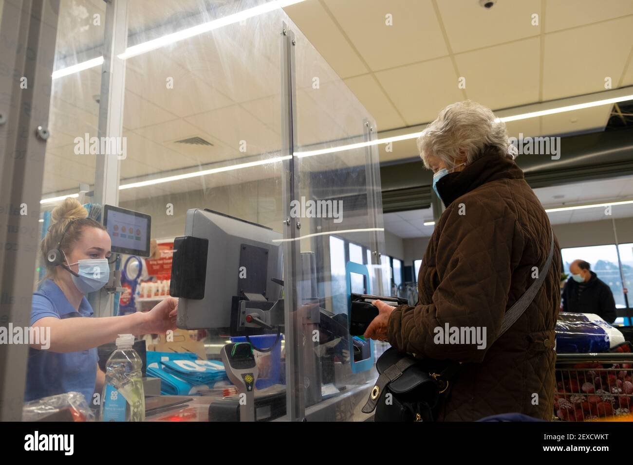 Cliente acquirente e lavoratore che indossa maschera Covid viso al Co Op supermercato checkout contatore cibo shopping coronavirus nel Regno Unito negozio Gran Bretagna KATHY DEWITT Foto Stock
