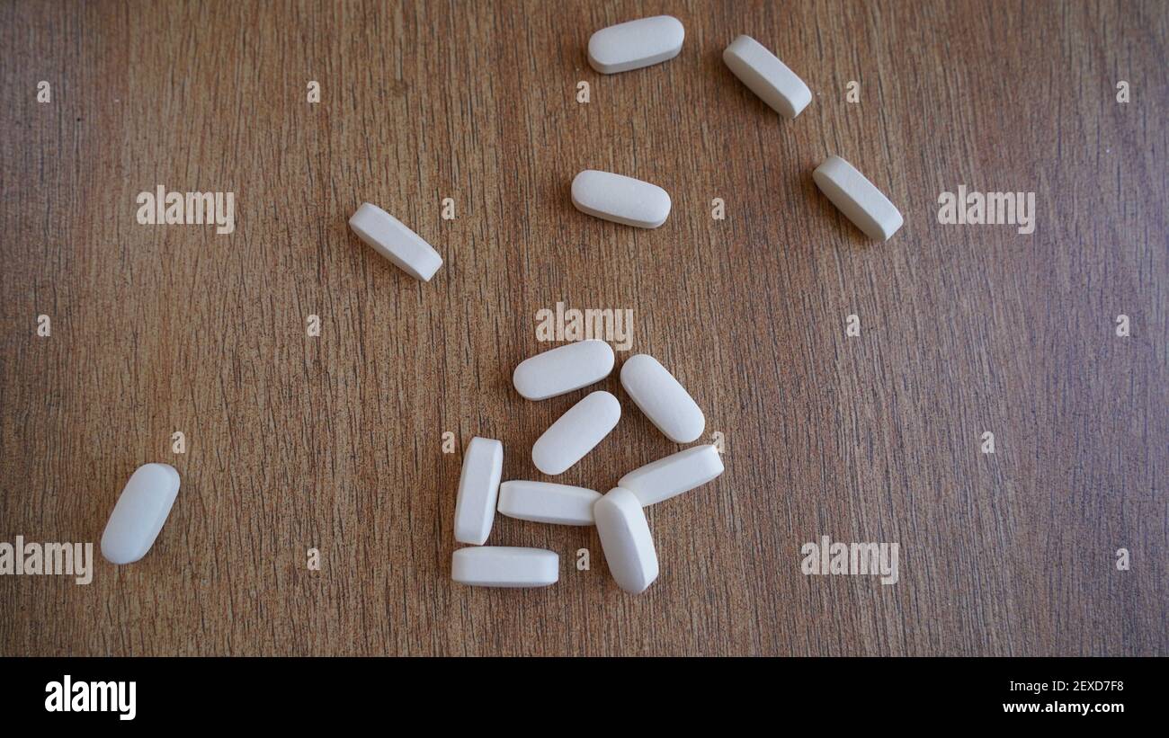 Cumulo di calcio, vitamina supplemento compresse isolato su sfondo di legno. Molte pillole mediche bianche e capsule per ossa forti. Rimani al sicuro e tieniti in salute Foto Stock