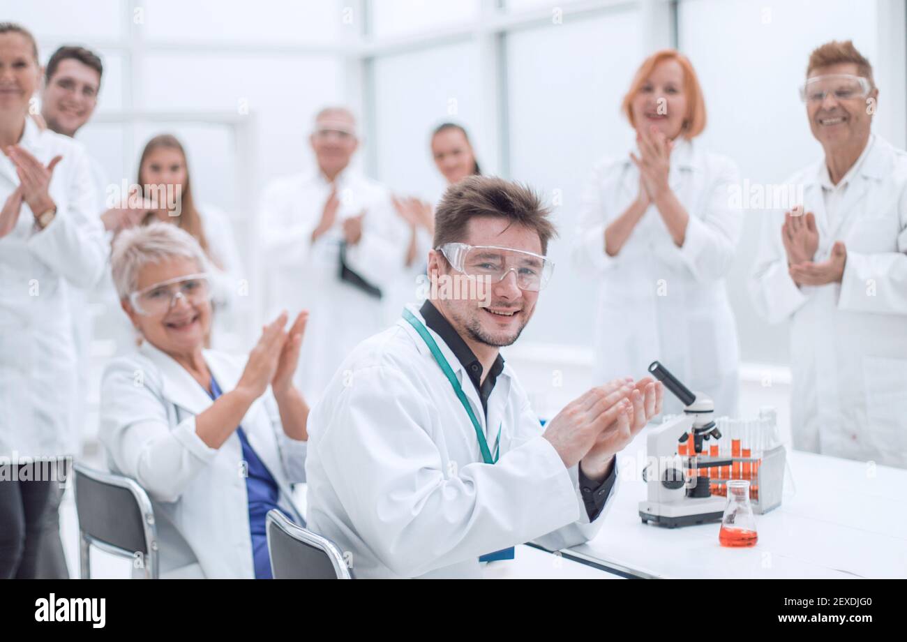 gruppo di giovani scienziati che si congratula con il collega per gli applausi Foto Stock