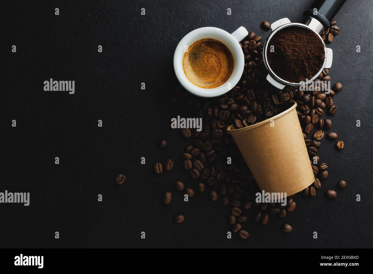 Concetto di caffè o zero sprechi. Chicchi di caffè in una tazza di carta con una tazza di caffè espresso su sfondo scuro. Foto Stock