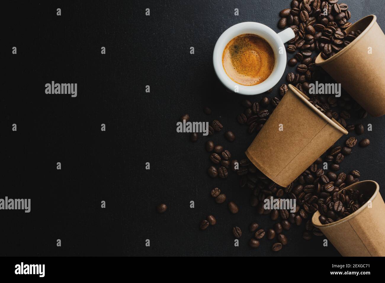 Concetto di caffè o zero sprechi. Chicchi di caffè in una tazza di carta con una tazza di caffè espresso su sfondo scuro. Foto Stock