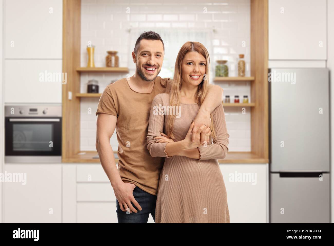 Giovane coppia allegra in posa all'interno di una cucina moderna Foto Stock