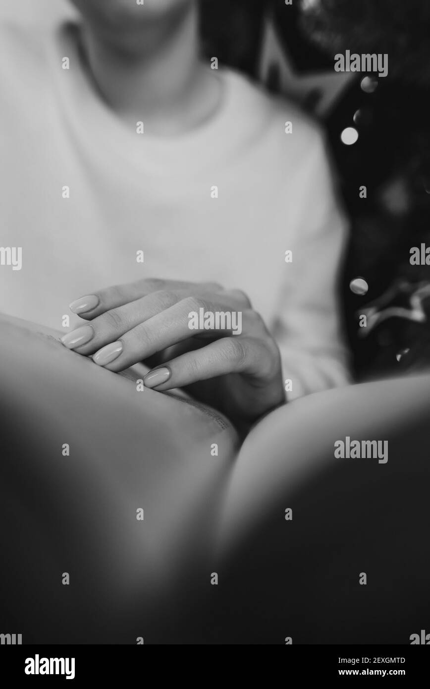 Donna in bianco leggere interessante libro di carta mentre si siede vicino albero di Natale con bokeh a casa. Bianco e nero. Accogliente foto invernale di signora relax Foto Stock