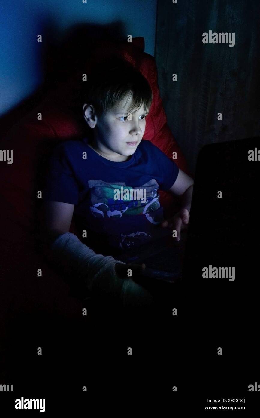 ritratto del ragazzo che usa il computer portatile mentre si è seduti su una sedia a sdraio Foto Stock