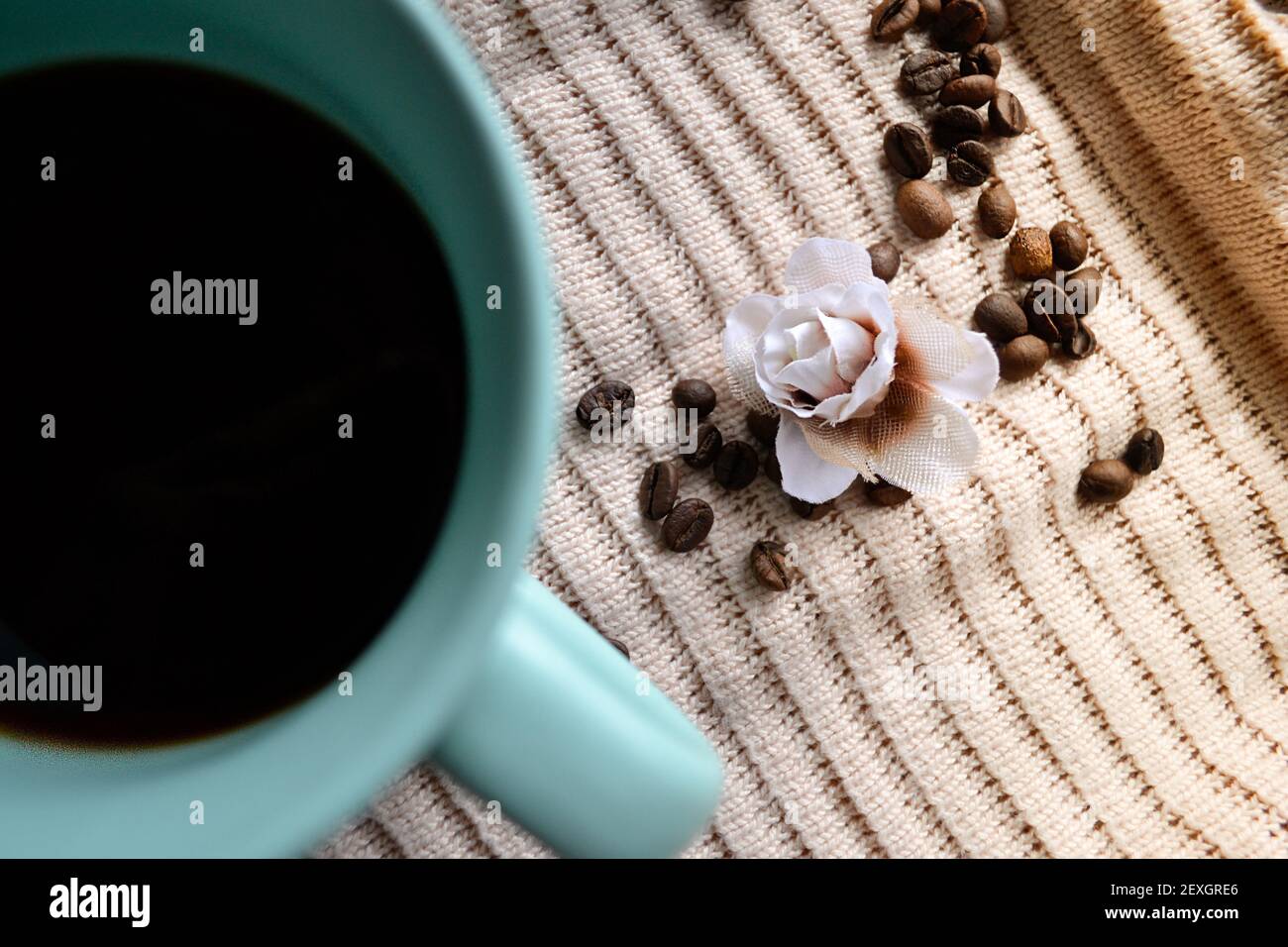 tazza di caffè su un panno lavorato a maglia accanto ai chicchi di caffè Foto Stock