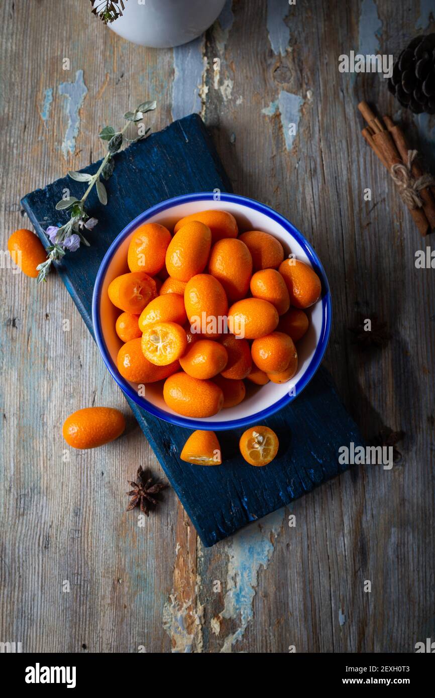 Vista dall'alto dei kumquat freschi nel piatto sullo sfondo naturale di legno. Cumquat o kumquat. Foto Stock