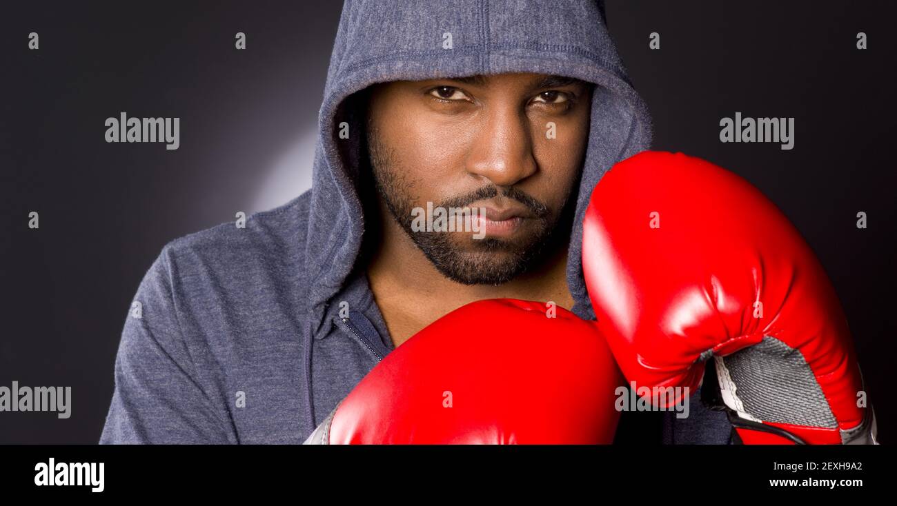 Solo maschio Atleta Boxer Strikes Fighter posa Hoodie Red Boxing Guanti Foto Stock