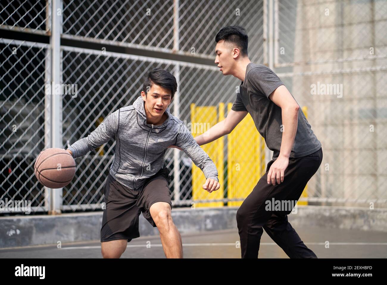 due giovani uomini adulti asiatici che giocano a basket uno a uno sul campo all'aperto Foto Stock
