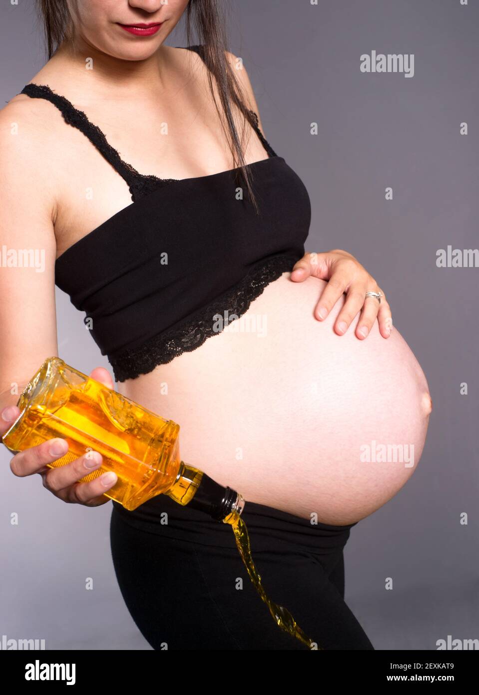 Donna incinta alcolico aspettandosi il bambino versa l'alcool svuota il flacone di Whiskey Foto Stock