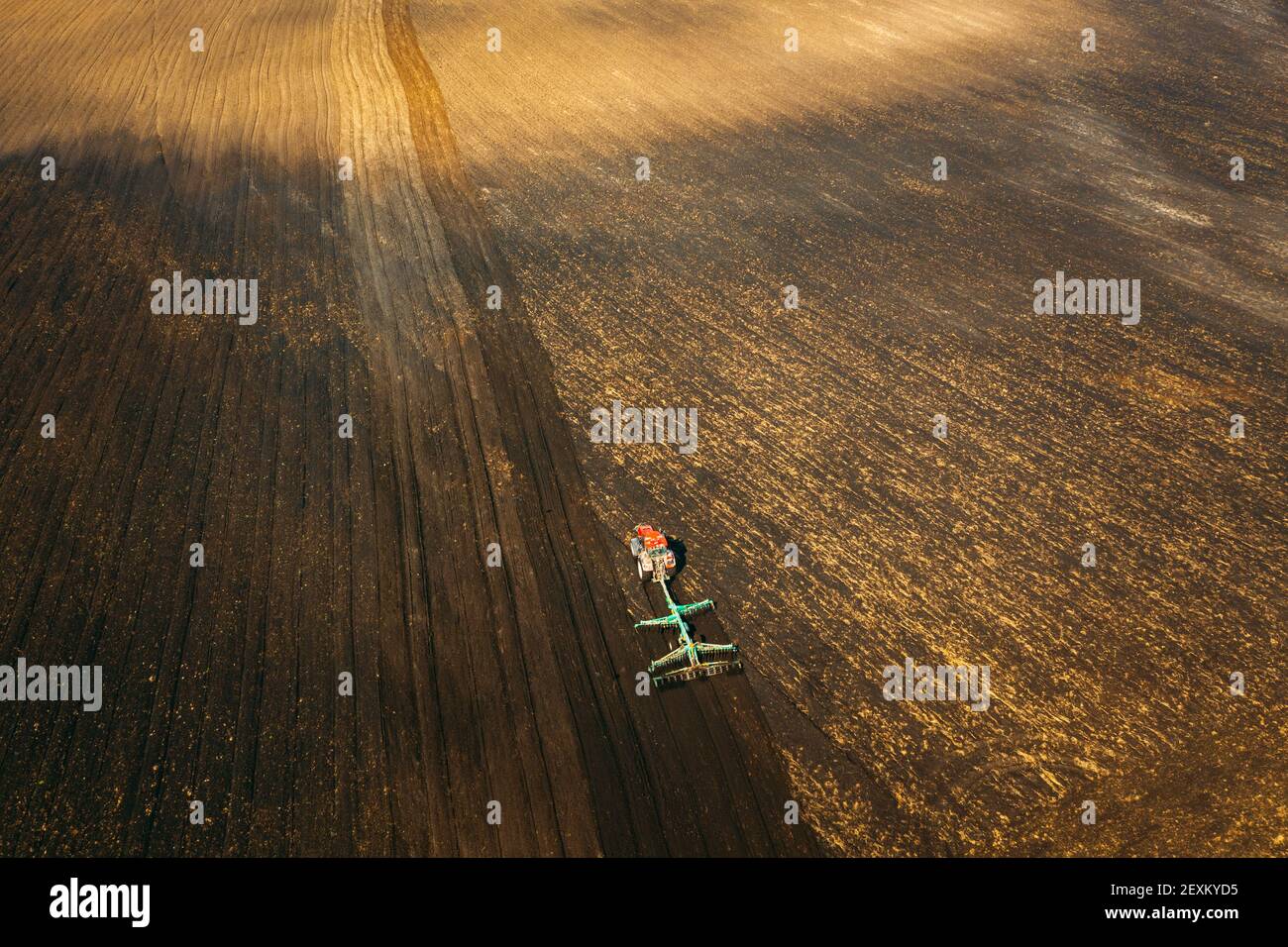 Vista aerea. Campo di aratura del trattore nella stagione primaverile. Inizio della stagione di primavera agricola. Coltivatore trainato da un trattore in campagna Rurale Foto Stock