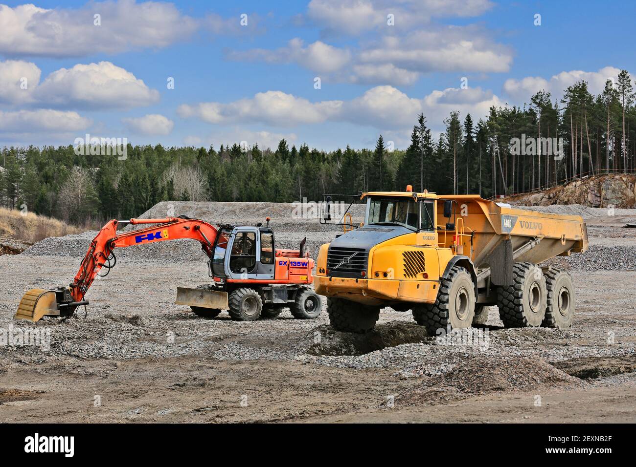 Escavatore gommato Hitachi EX 135W e trasportatore articolato o dumper Volvo A40D in cantiere in primavera. Finlandia. 25 marzo 2017. Foto Stock