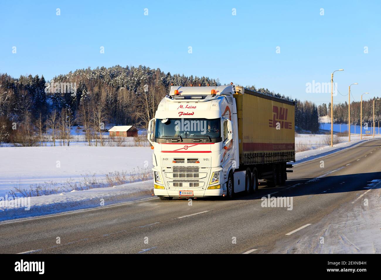 Il carrello bianco Volvo FH M. Leino tira il rimorchio DHL sull'autostrada 52 il giorno di sole dell'inverno. Salo, Finlandia. 11 febbraio 2021. Foto Stock
