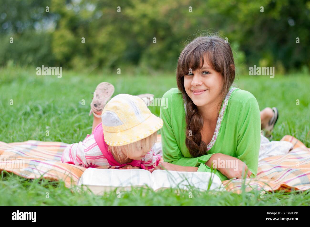 Due sorelle che leggono un libro all'aperto Foto Stock