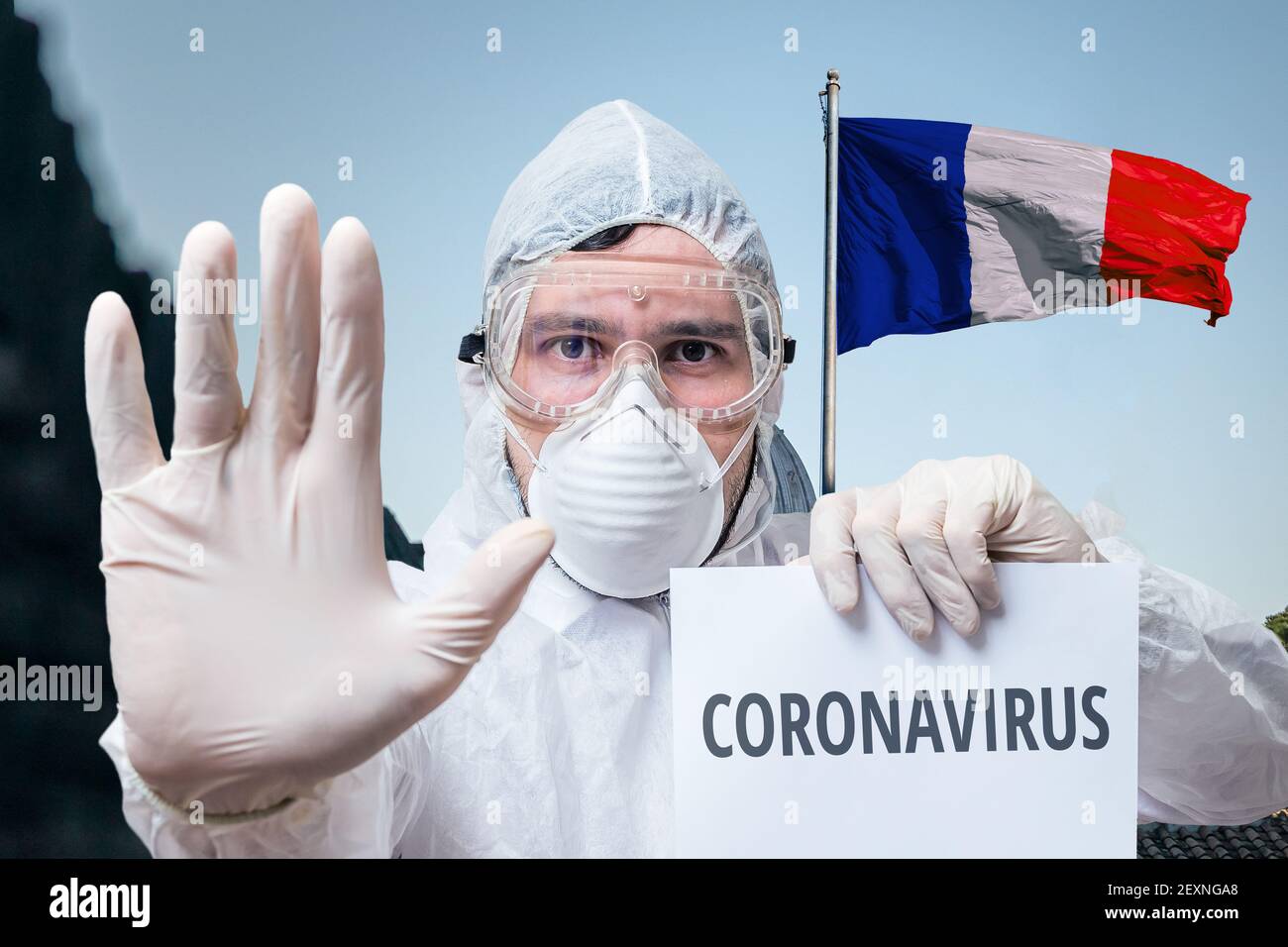 Medico in tute avverte di infezione da coronavirus in Francia. Bandiera francese sullo sfondo. Foto Stock