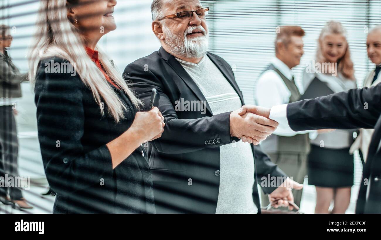 primo piano: due uomini d'affari che scuotono le mani nella hall dell'ufficio Foto Stock
