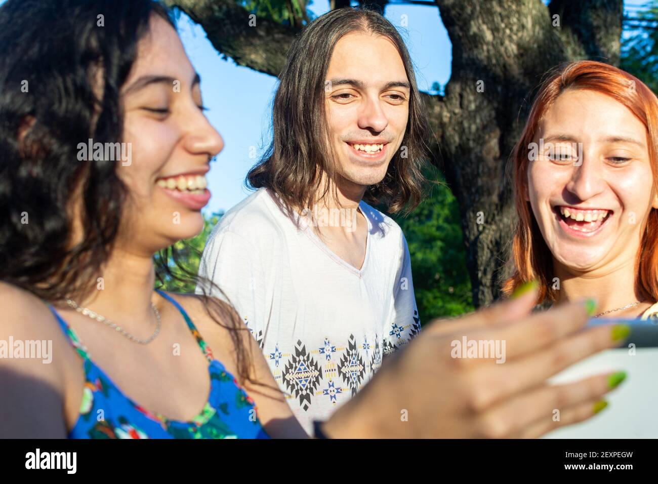 Un bel colpo di tre giovani adulti che ridono mentre si guarda su un tablet Foto Stock