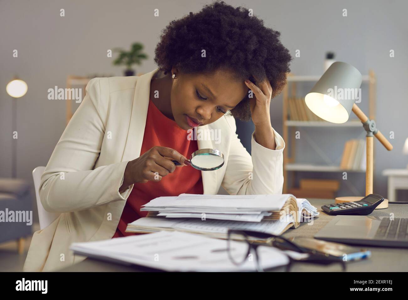 Commerciante donna d'affari che tiene la lente d'ingrandimento sopra la fattura sul posto di lavoro Foto Stock