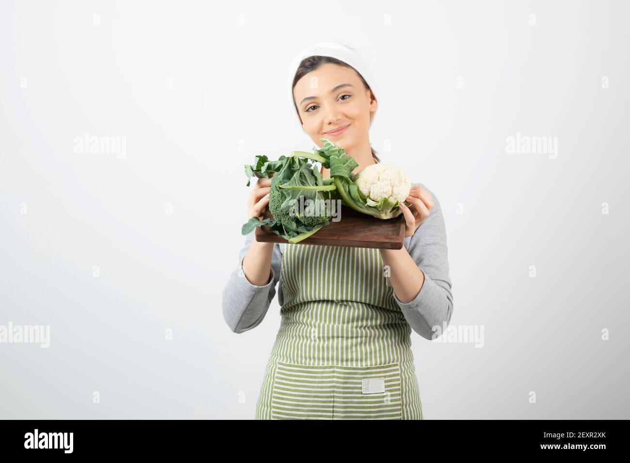 Immagine di una donna sorridente e attraente che tiene un piatto di legno di cavolfiori Foto Stock