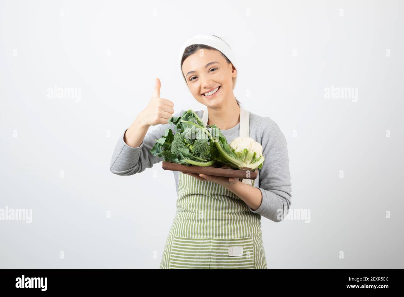 Immagine di una donna sorridente attraente con un piatto di legno di cavolfiori Foto Stock