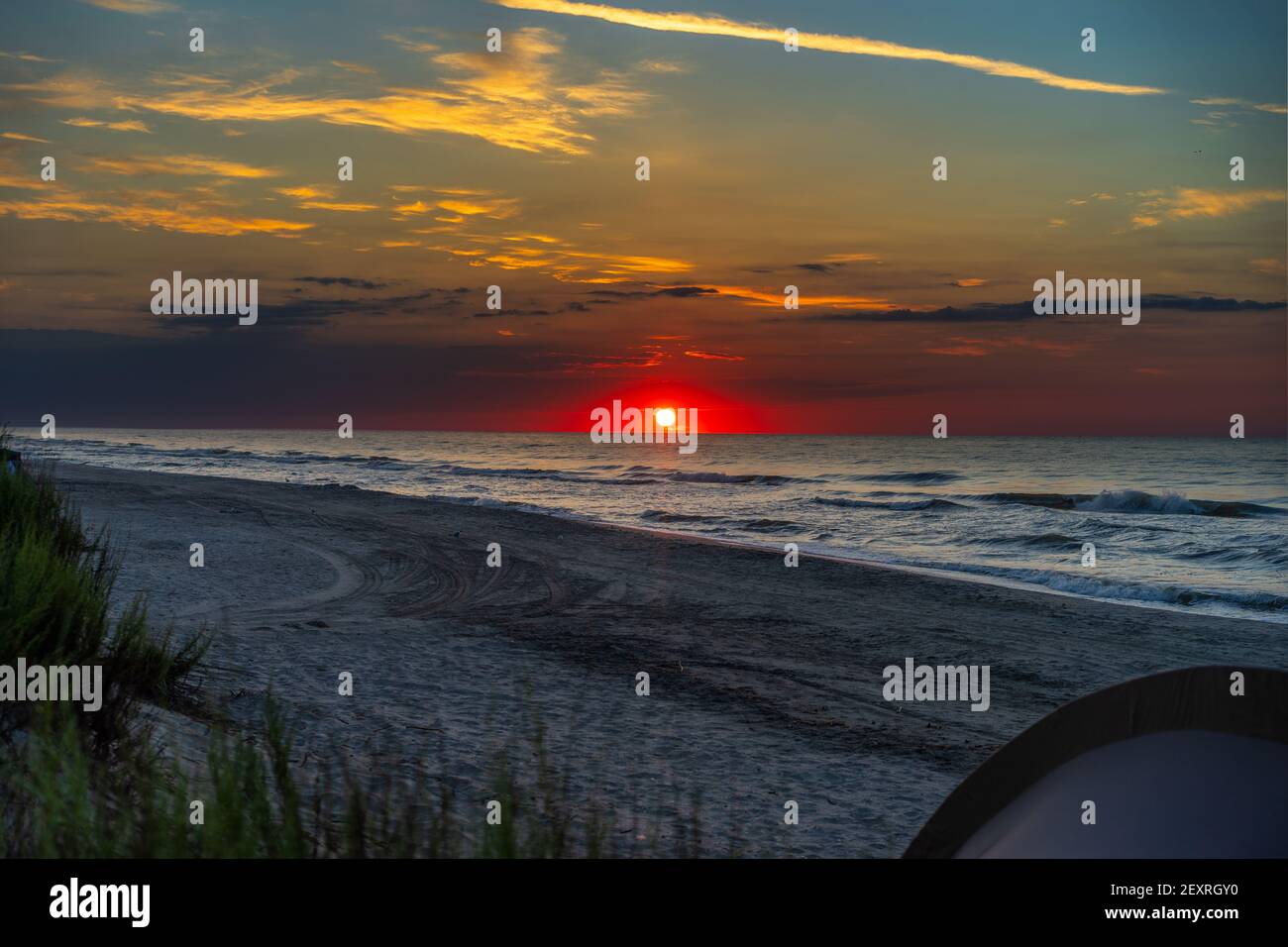 Vista panoramica sulla bellissima alba rossa sulla costa del mare e tenda da campeggio sulla spiaggia al mattino d'estate. Foto Stock