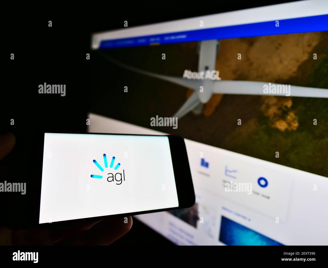 Persona in possesso di smartphone con logo della società australiana di energia elettrica e gas AGL sullo schermo di fronte alla pagina web. Focus sul display del cellulare. Foto Stock