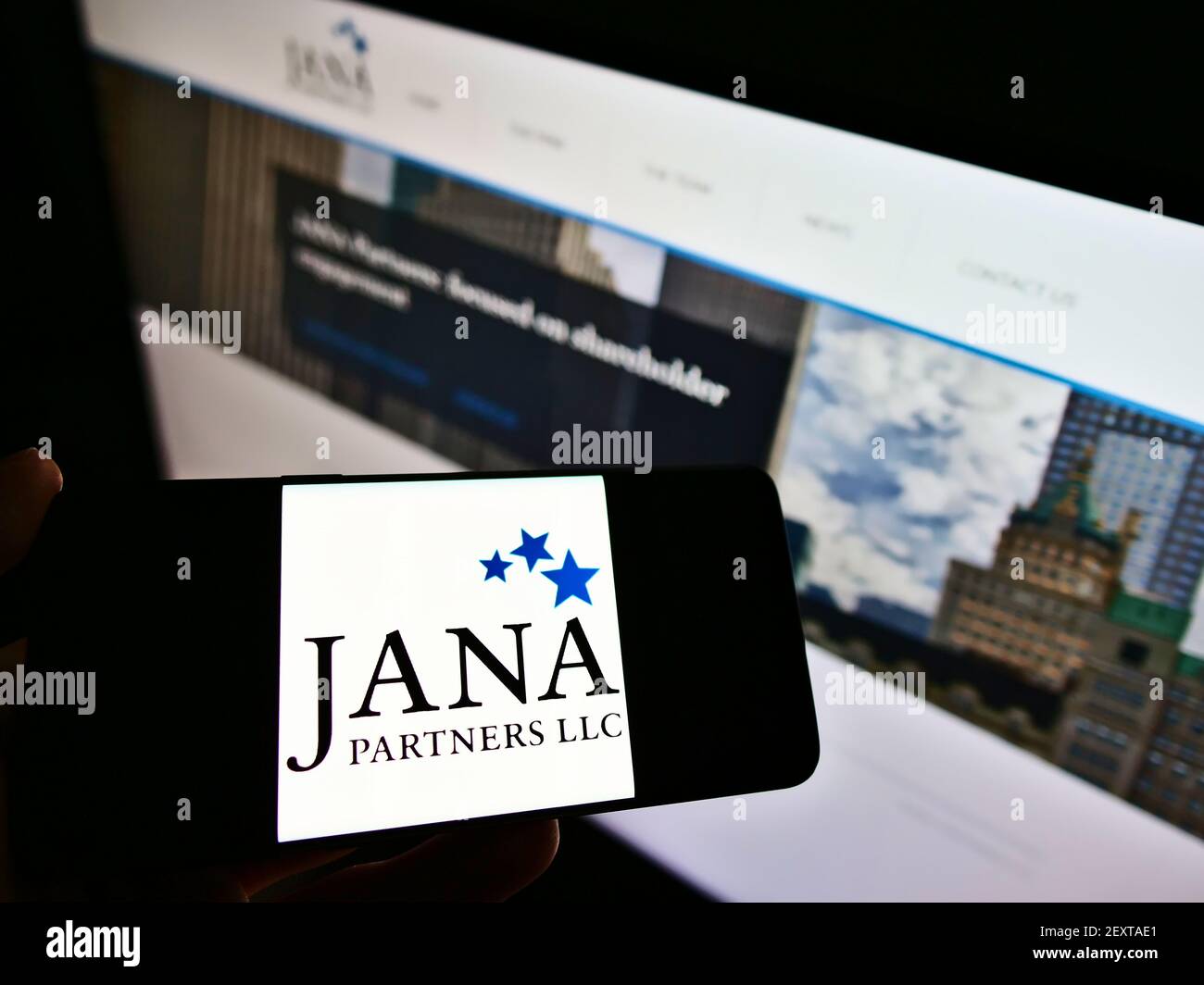 Persona che detiene smartphone con il logo della società di investimento statunitense JANA Partners LLC sullo schermo di fronte al sito Web. Mettere a fuoco il display del telefono. Foto Stock