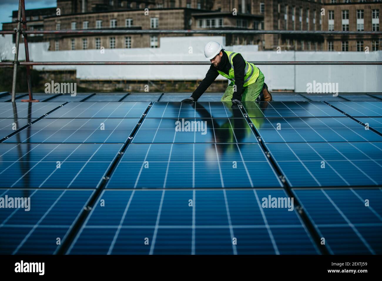 Operatore che monta pannelli solari sul tetto degli uffici del City Council di Edimburgo, Waverley Court, Edimburgo, UK. Foto Stock