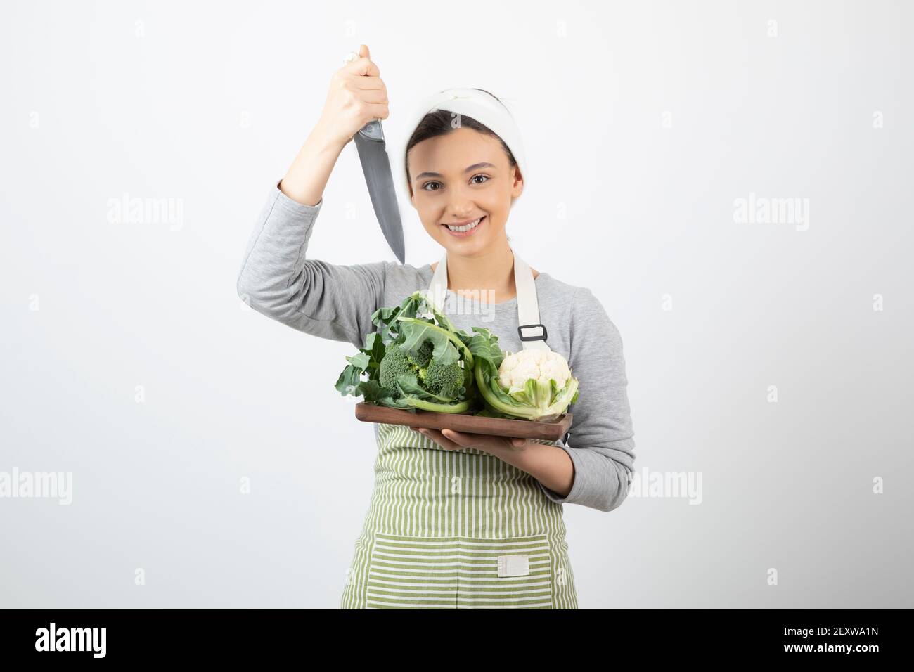Immagine di una donna sorridente attraente che tiene un coltello con una piastra di legno Foto Stock