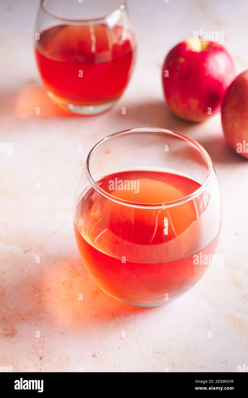 Due bicchieri di mela Pink Lady con due mele fresche sullo sfondo. Foto Stock