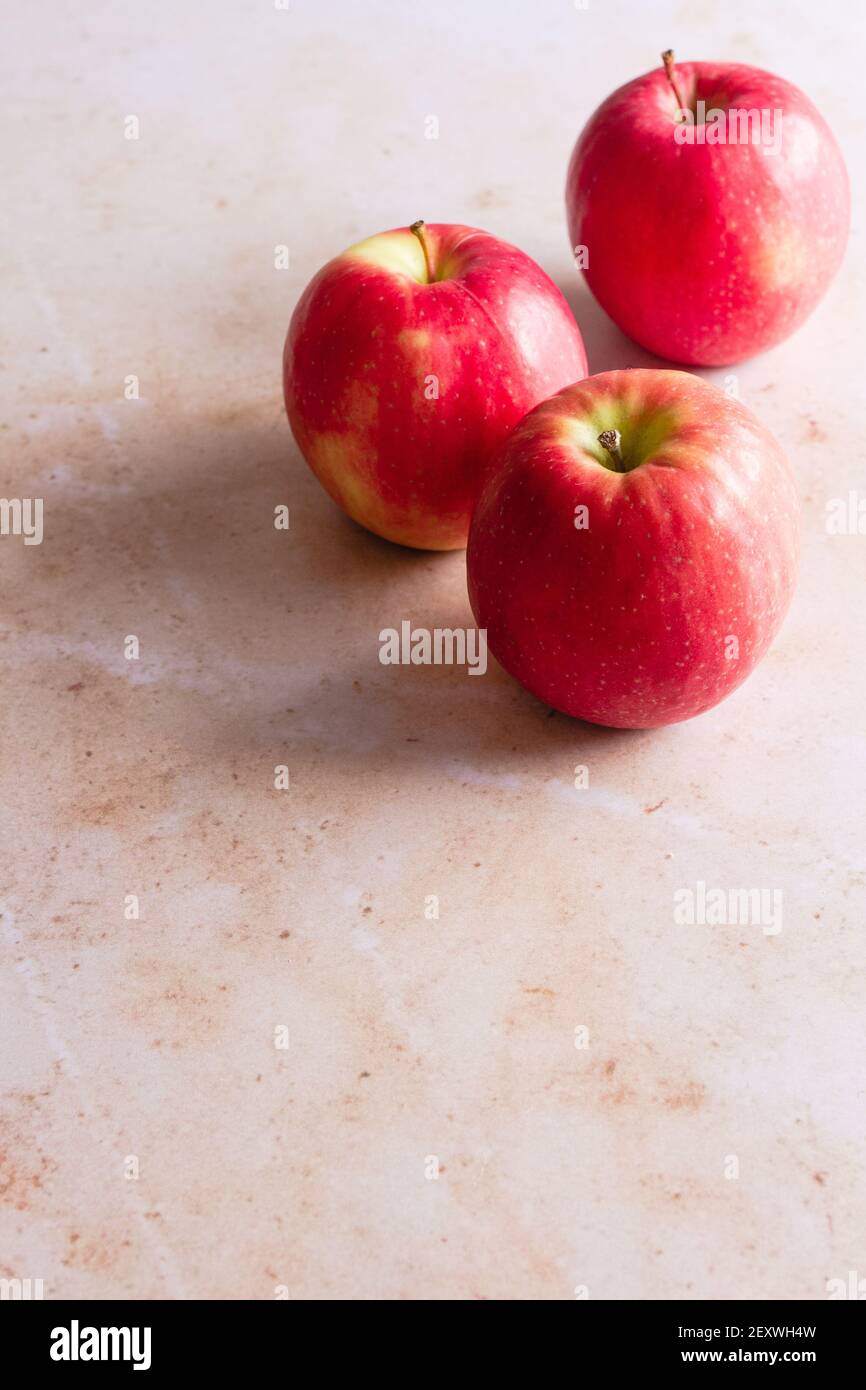 Tre mele Pink Lady su uno sfondo di marmo rosa. Foto Stock