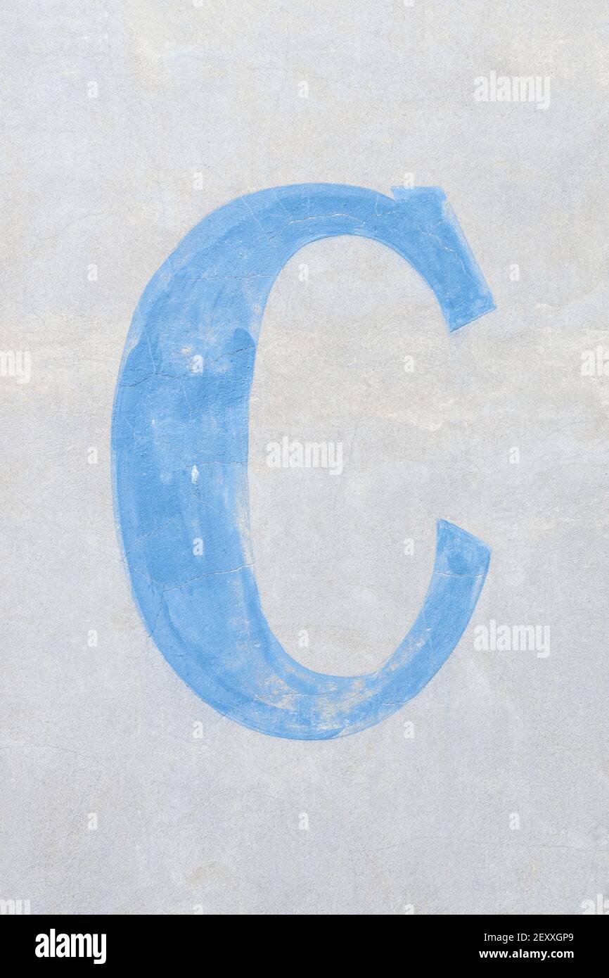 Lettera blu chiaro C in carattere serif su una luce parete grigia Foto Stock
