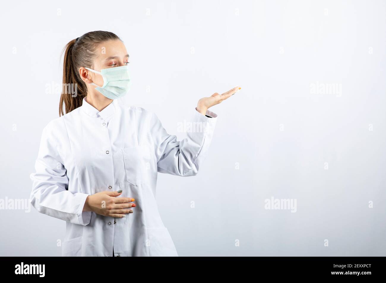 Donna medico in uniforme bianca che indossa una maschera medica Foto Stock