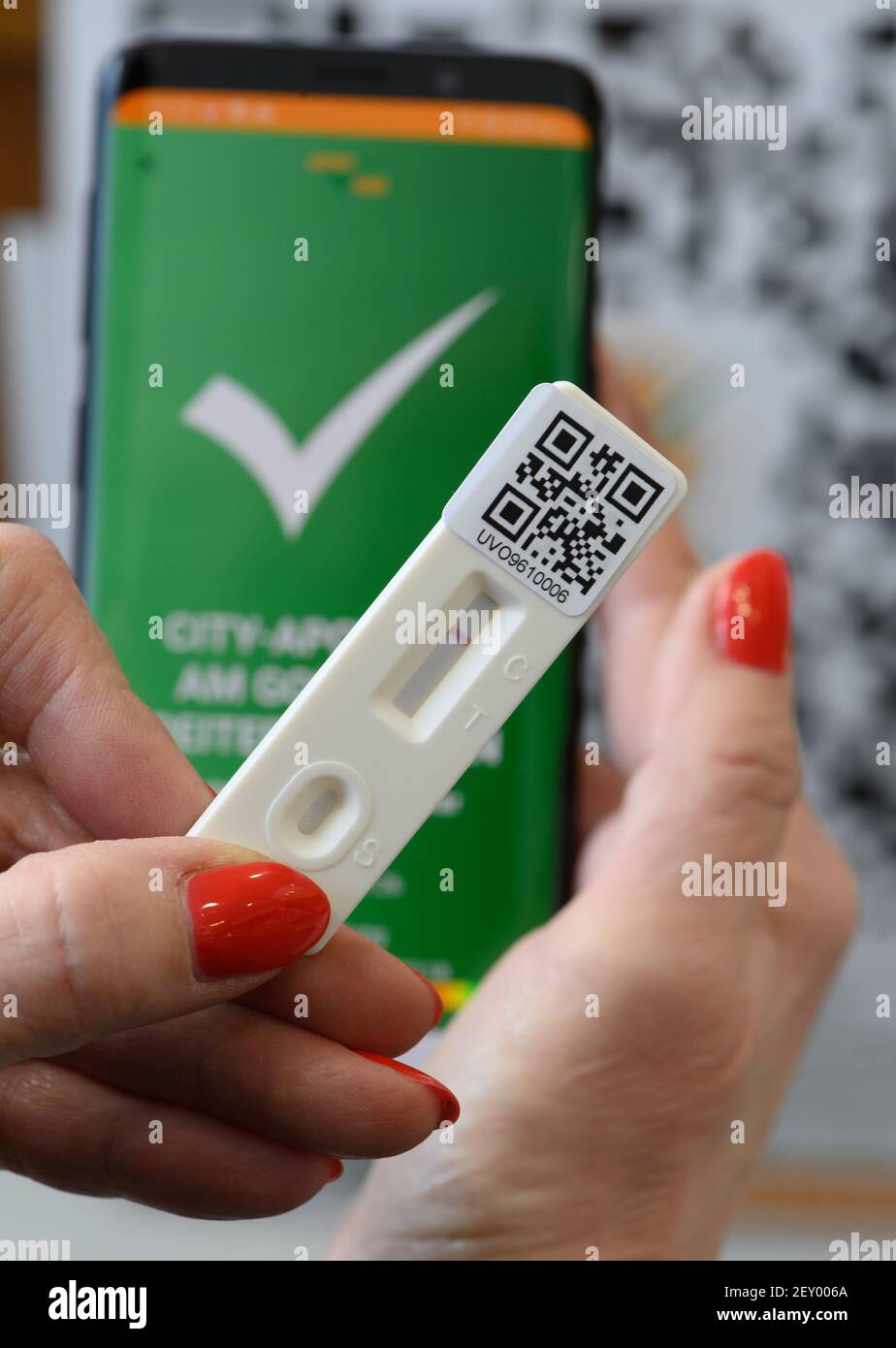 Dresda, Germania. 05 marzo 2021. Una donna ha una cassetta di test rapido  Covid-19 con il risultato negativo nelle sue mani in farmacia, sullo sfondo  l'app della startup sassone 'pass4all' può essere