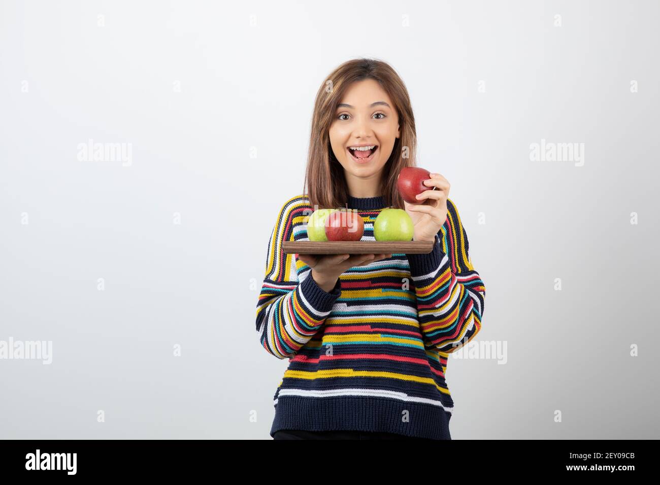 Adorabile giovane ragazza in abiti casual che tiene mazzo di mele Foto Stock