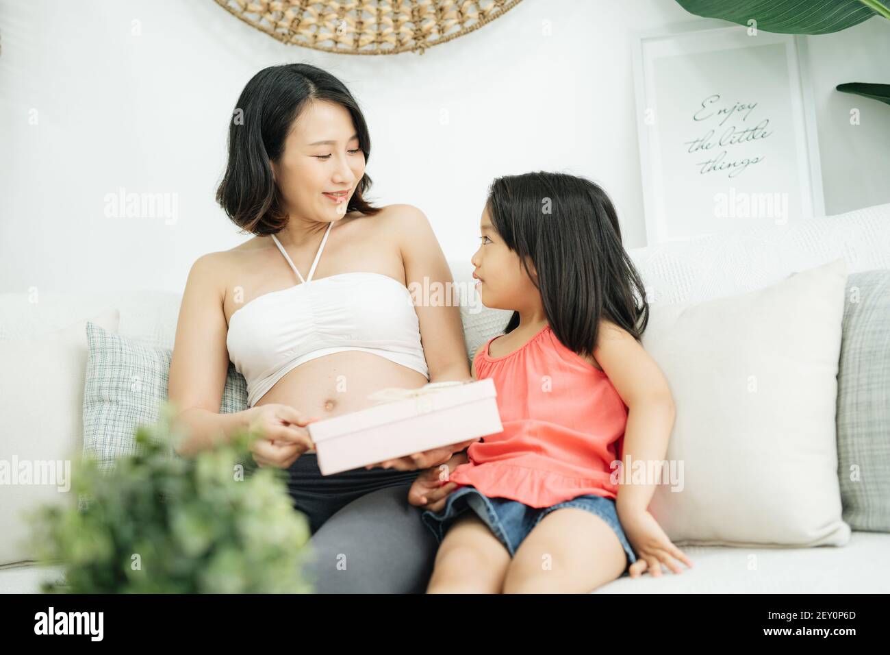 Primo piano di adorabile bambina che dà scatola regalo a mamma in attesa, felice compleanno Mummy Foto Stock