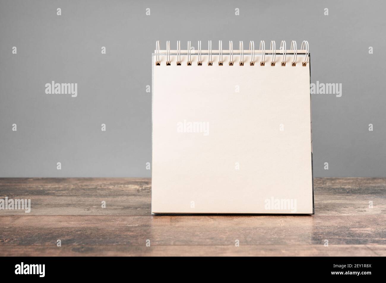 blocco note mockup. Mockup di blocco note con bordo a spirale vuoto con sfondo grigio chiaro e tavolo in legno. Modello per il posizionamento del progetto. Foto Stock