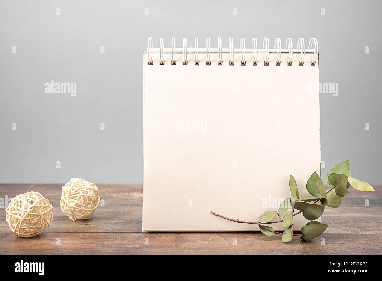 modello di notebook con supporti di carta bianchi su tavolo di legno su sfondo grigio decorato con fiori secchi Foto Stock